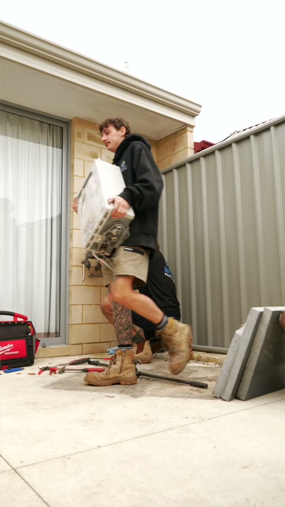 Plumber carrying in a replacement hot water unit