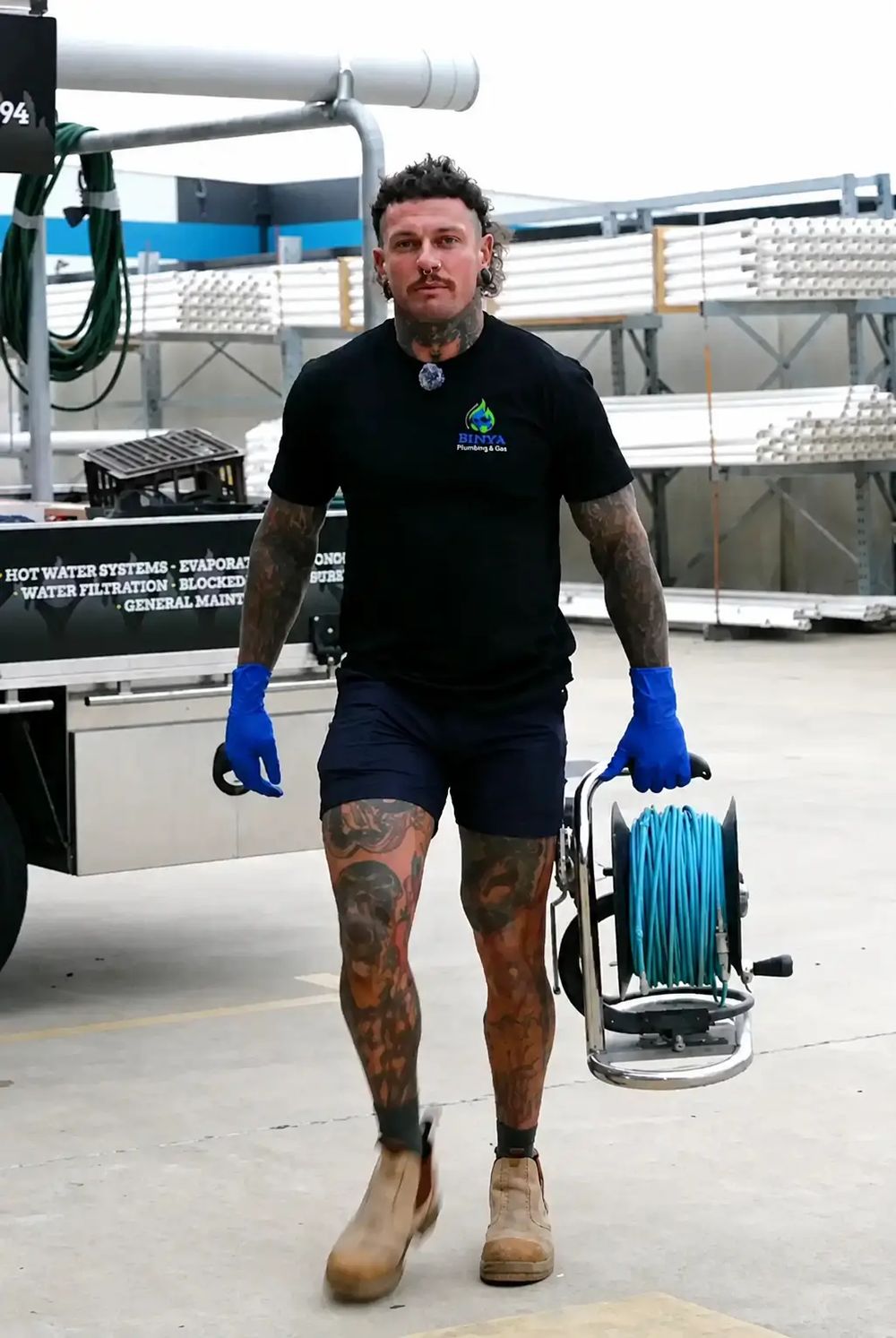 Birdy's plumber carrying a drain jetter hose reel